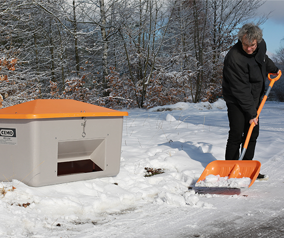 CEMO GFK Schneeschaufel und Streugutbehälter Mann räumt Schnee mit CEMO GFK Schneeschaufel. Im Hintergrund steht ein Streugutbehälter von CEMO.